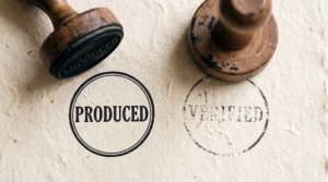 Close-up of two rubber stamps: one crisp reading PRODUCED, one incomplete reading VERIFIED.