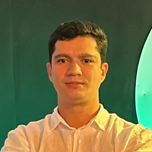 Portrait of Humberto Martins in a light shirt against a deep green wall lit by a pale oval light